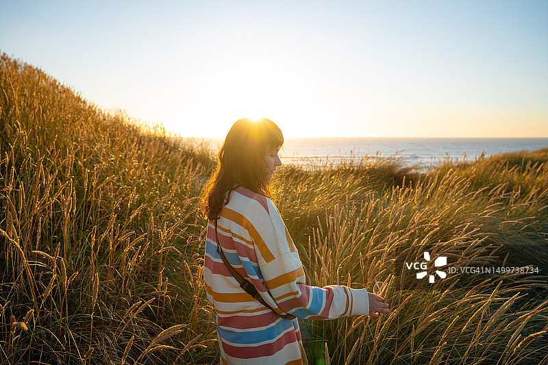 日落时分在卡特wijk aan Zee海滩上散步的女人图片素材