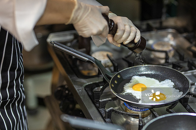 在厨房工作的厨师，烹饪鸡蛋，准备早餐图片素材