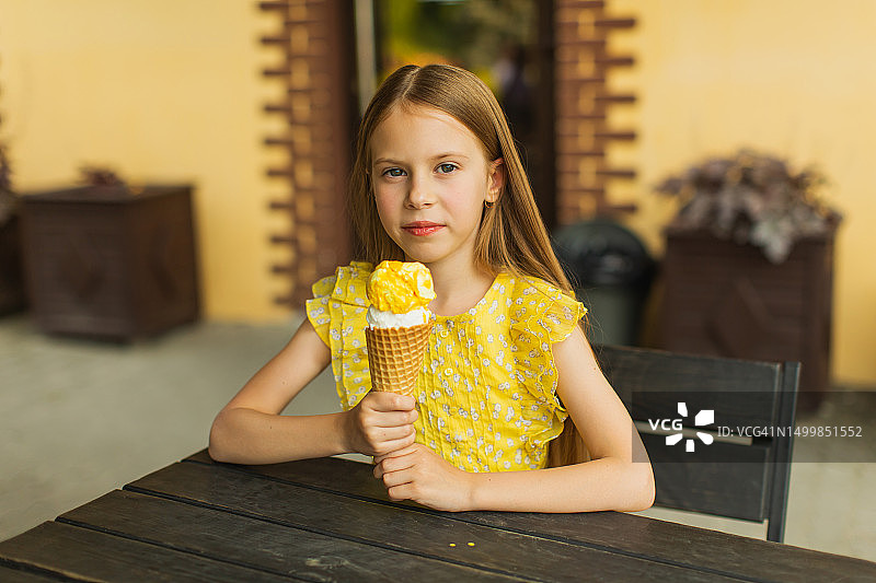 穿黄色连衣裙吃冰淇淋的金发女孩，夏日童年图片素材