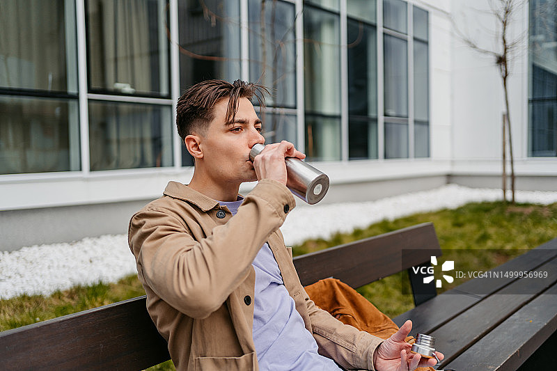 在户外用保温瓶喝咖啡或水的年轻男人图片素材