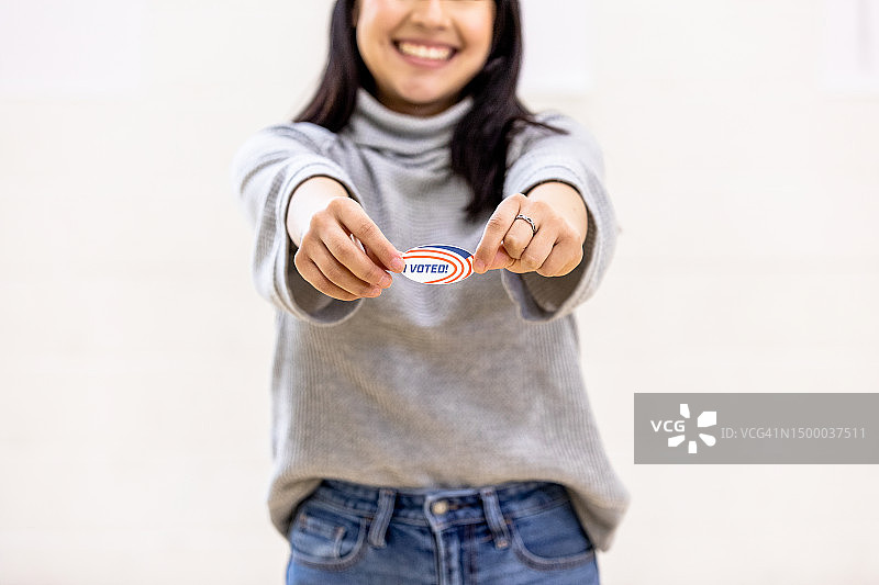 年轻女子自豪地展示“我已投票”贴纸，面带微笑图片素材