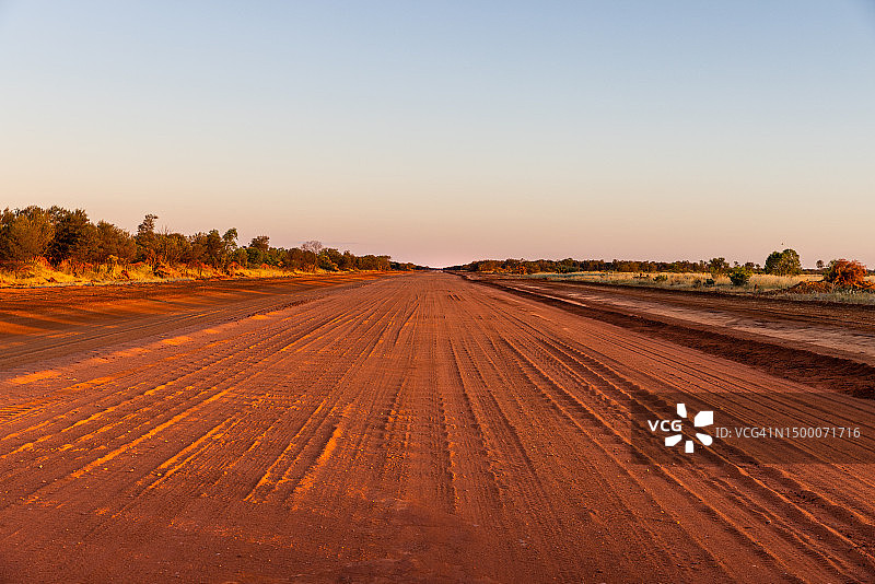 澳大利亚北部地区塔纳米沙漠黎明时分的瓦楞土路图片素材