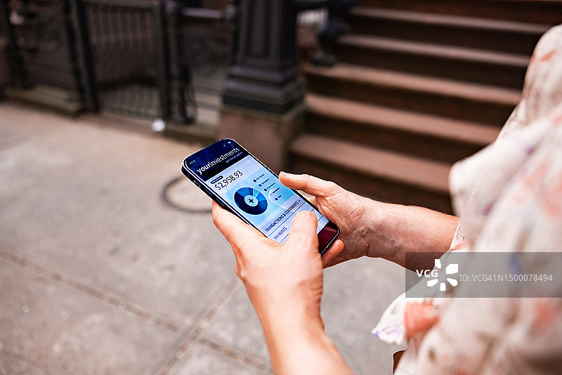 年轻女人在街上行走时查看她的银行账户图片素材