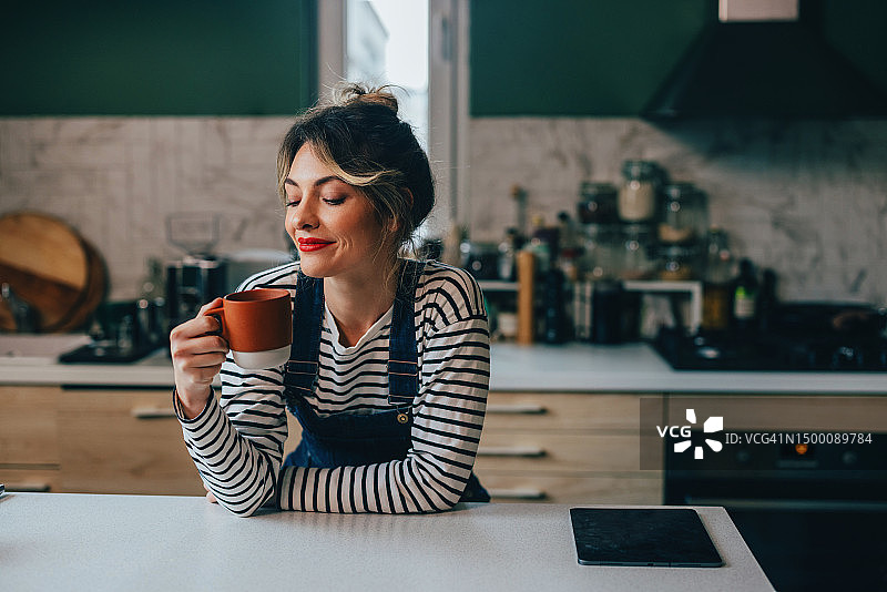快乐美丽的白人妇女在家放松喝茶图片素材