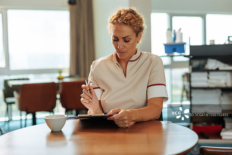 金发女佣坐着填写表格图片素材