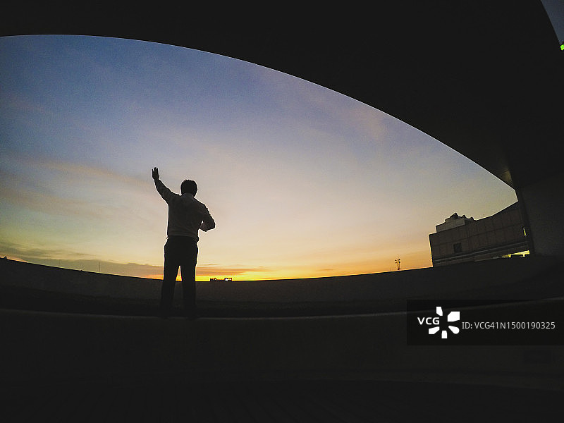 日落时分，天空和建筑物背景下的男人剪影背影图片素材