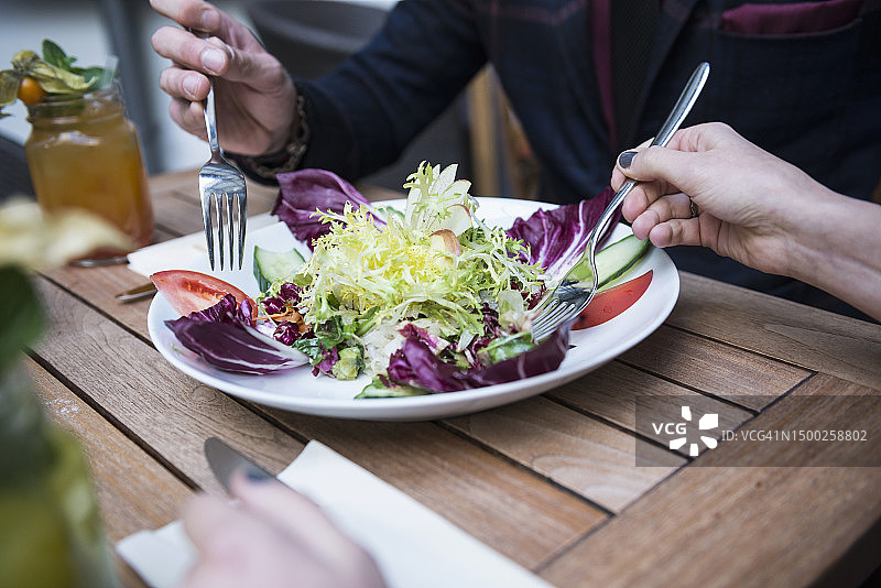 两个人拿着叉子吃沙拉的局部图图片素材