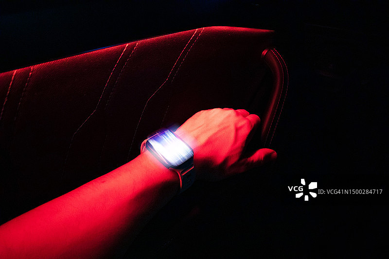 汽车内，手腕上带有红色灯光的未来智能手表图片素材