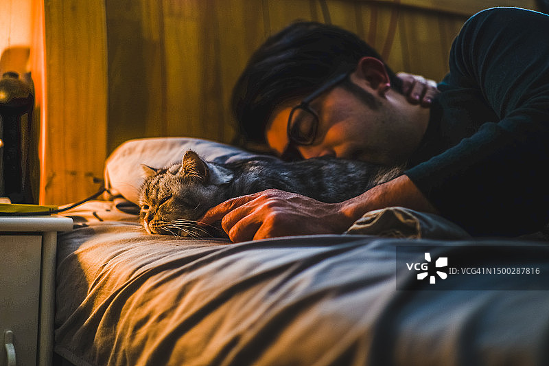 亚洲男人和他的猫一起睡觉图片素材