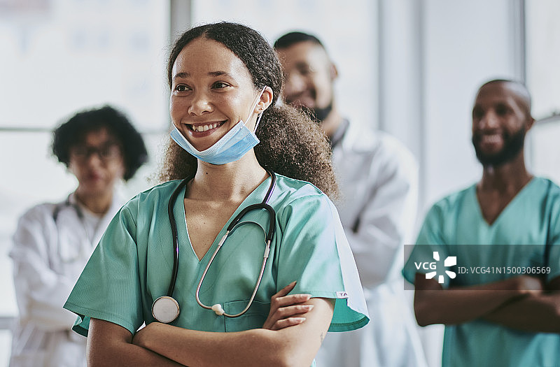 一位年轻护士双手交叉站立，面带微笑，背景是三位未被认出的医生和护士图片素材