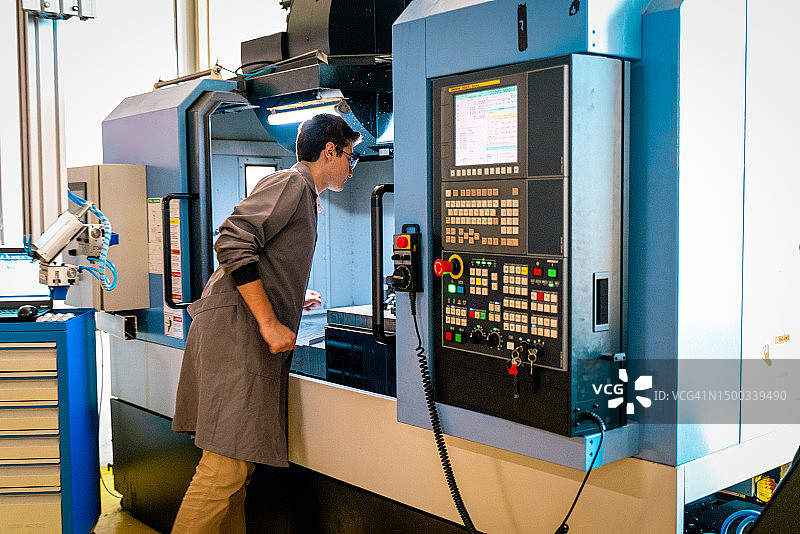 在职业技术培训学校使用数控机床的年轻学生图片素材