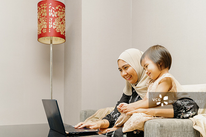 在客厅使用笔记本电脑的亚洲女性和女儿图片素材