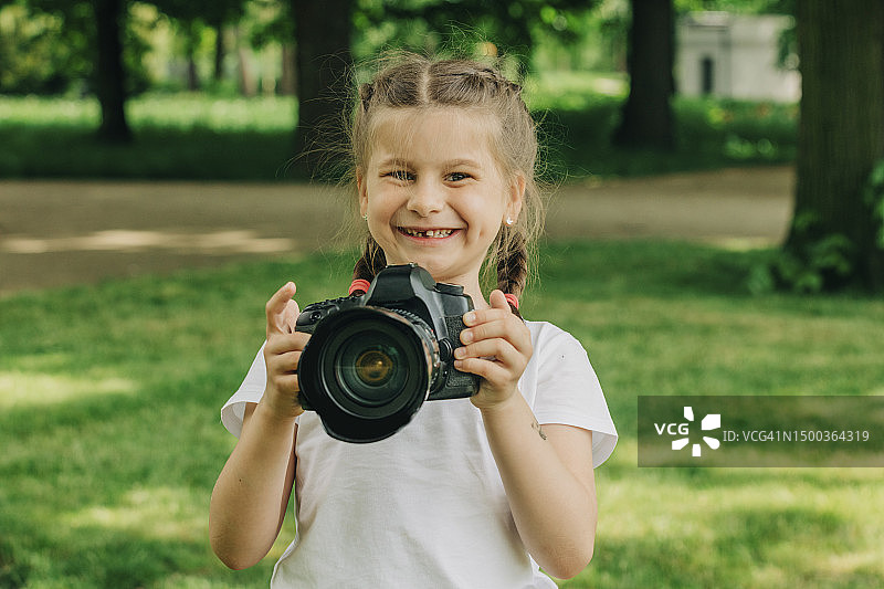 在公园里拿着相机的快乐女孩图片素材