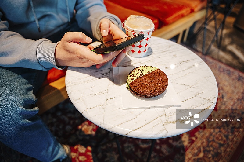 男孩在咖啡馆用手机拍摄蛋糕图片素材