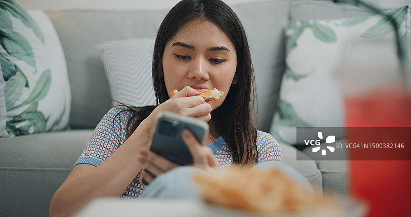 吃华夫饼并在手机上使用社交媒体的年轻亚洲Z世代女人图片素材