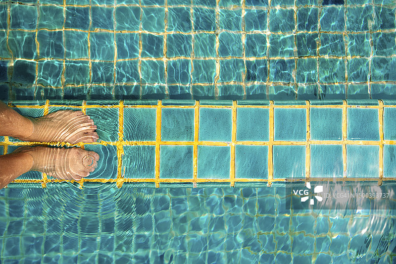 游泳池瓷砖地板上的女人的腿图片素材