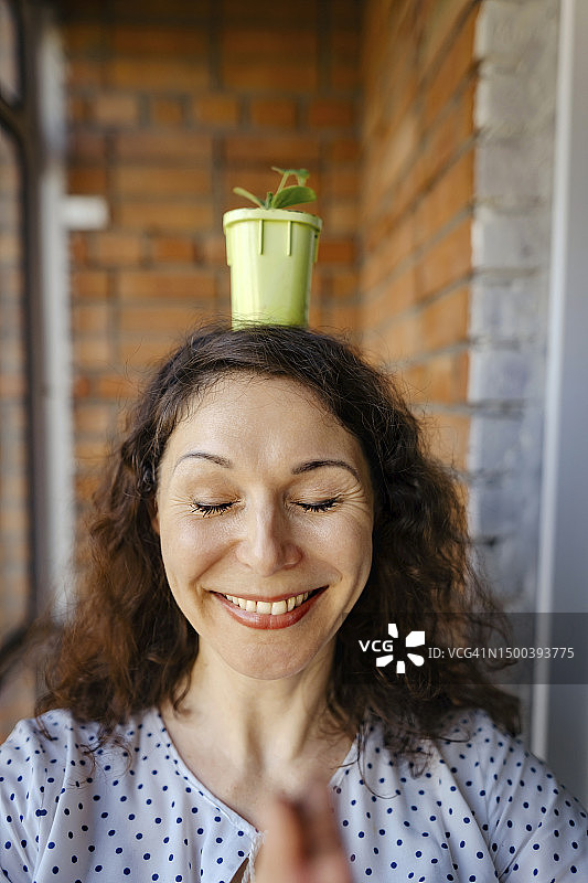 快乐的女人头顶盆栽冥想图片素材