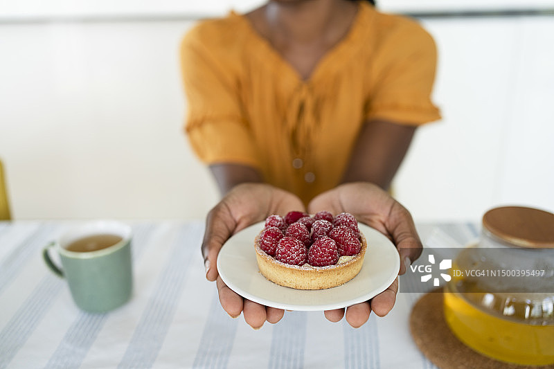 女性在家中拿着盘子里的覆盆子馅饼图片素材