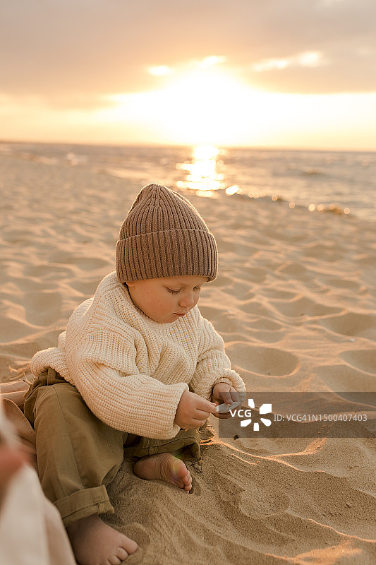 戴针织帽在海滩玩耍的可爱男孩图片素材