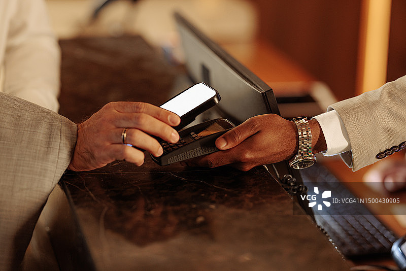 男人在酒店前台用手机支付的特写照片图片素材