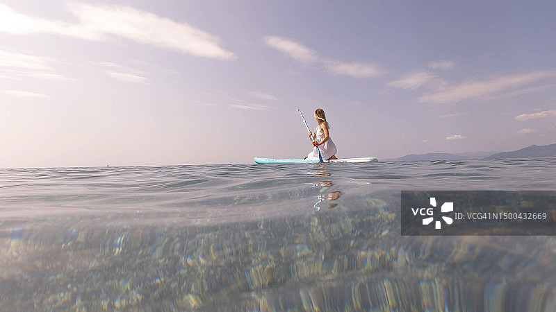 年轻女人在晨光中划桨图片素材