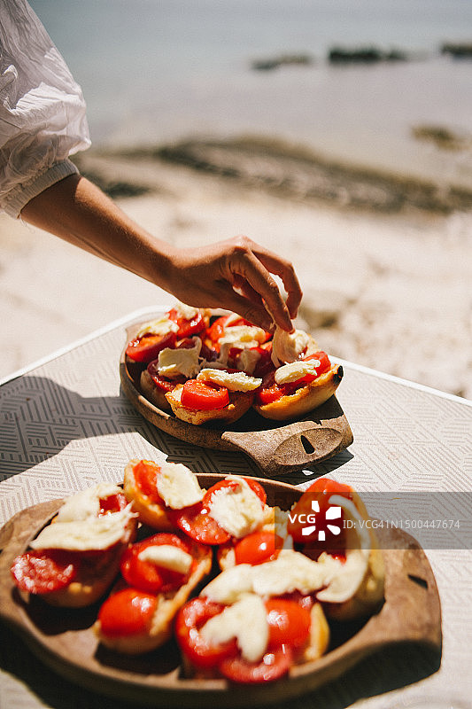 女人在卡普雷塞三明治上做最后的润色图片素材