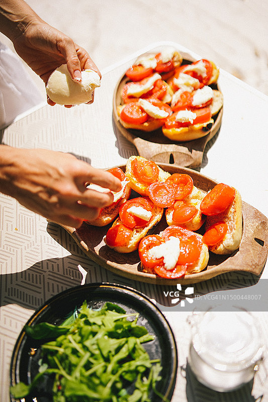 女人在卡普雷塞三明治上做最后的润色图片素材