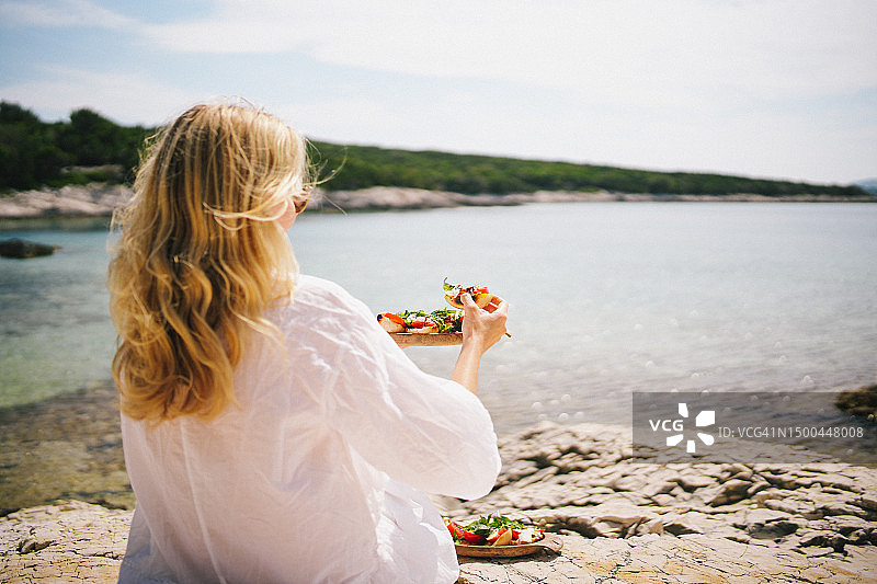 年轻女人吃新鲜的三明治图片素材