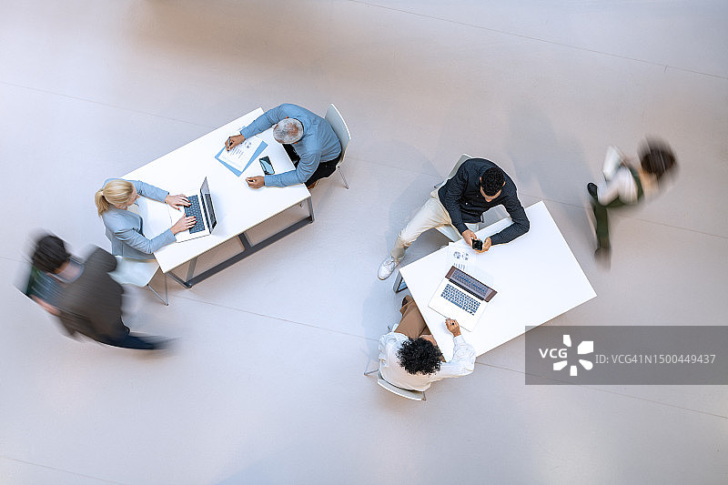 同事在两张桌子旁走动的航拍图片素材