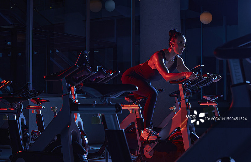运动型女人在健身房的动感单车上训练图片素材
