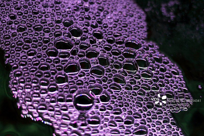 紫色光效下漂浮在水面的水泡图片素材