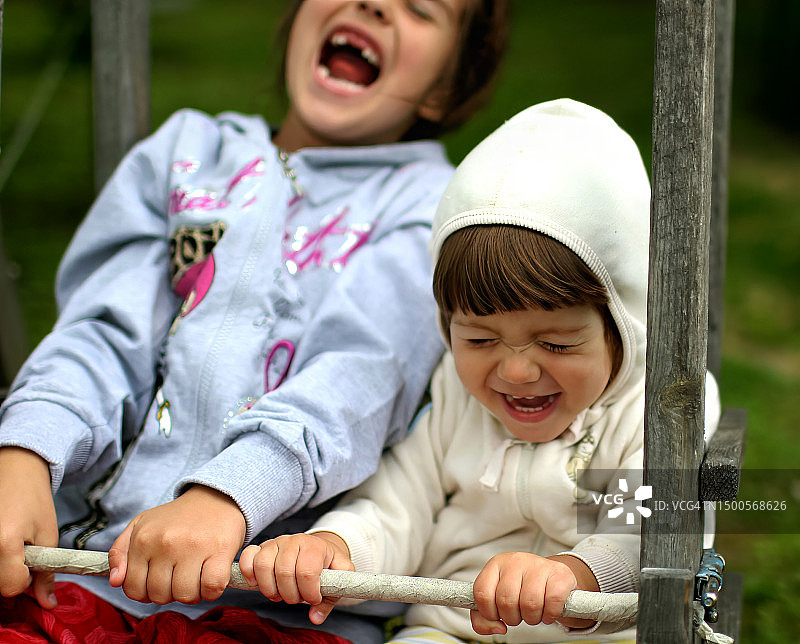 两个小女孩在花园里笑着玩耍，乡村场景，幸福图片素材