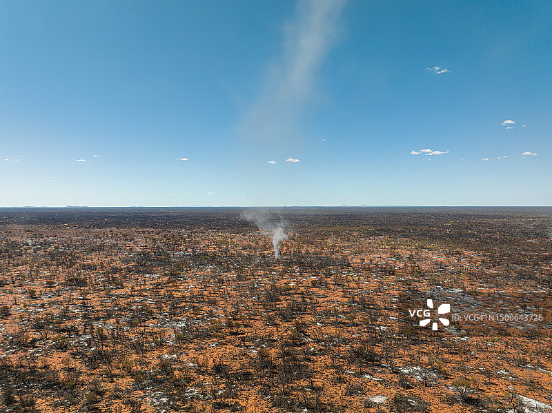 无人机在晴朗的一天拍摄的澳大利亚北部地区塔纳米沙漠中穿过烧毁景观的尘旋风图片素材