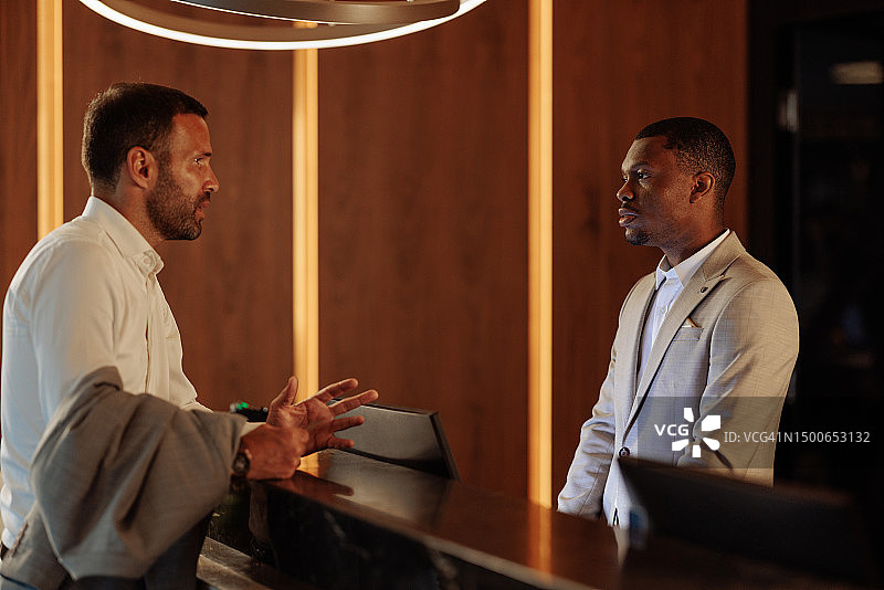 男人向酒店前台抱怨服务图片素材
