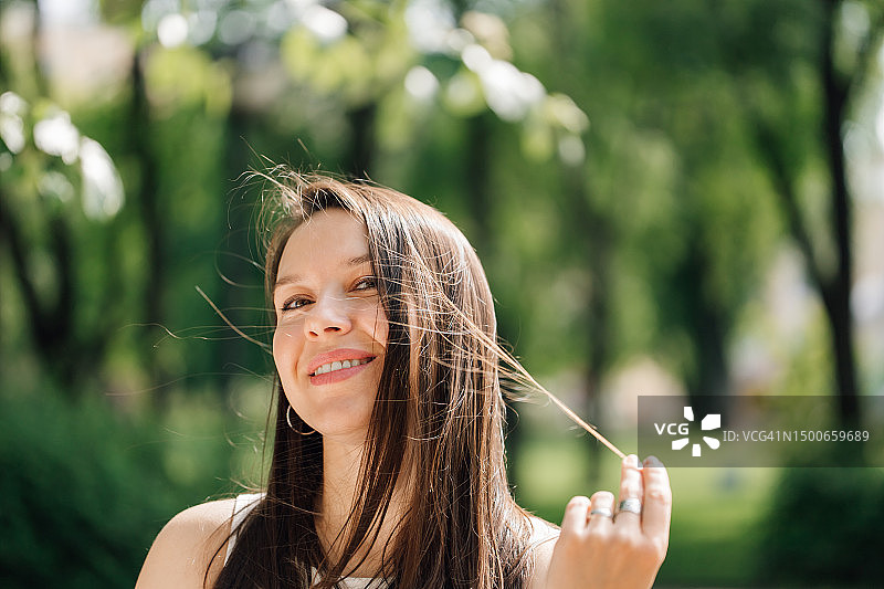 长棕色头发的迷人女士，面带喜悦地看着镜头图片素材