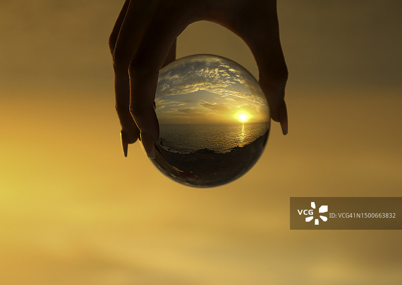 手持水晶球拍摄拉斯帕尔马斯日落景观图片素材