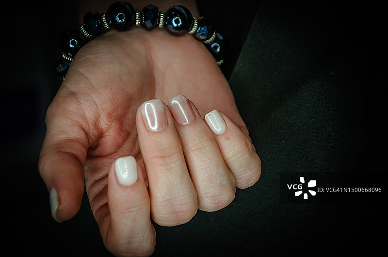 涂指甲油的女子手部特写，黑色背景图片素材