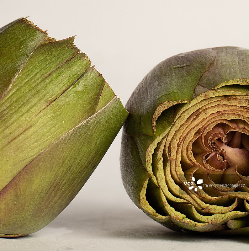 特写：白色背景上切成两半的生朝鲜蓟图片素材