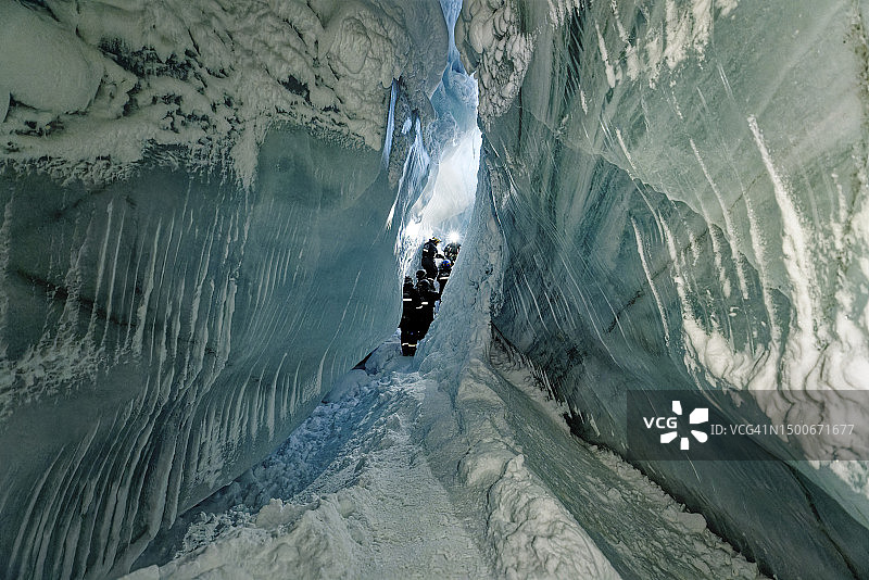 在挪威斯匹次卑尔根岛的洞穴中探险的男人们的后视图图片素材