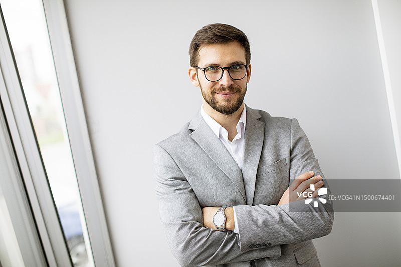站在办公室墙边的年轻现代商人图片素材
