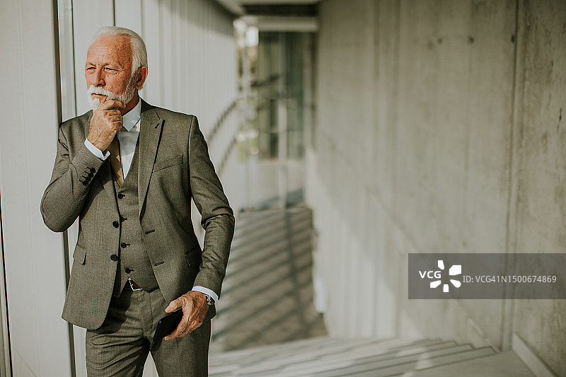 一位年长的商人站在办公室走廊里图片素材