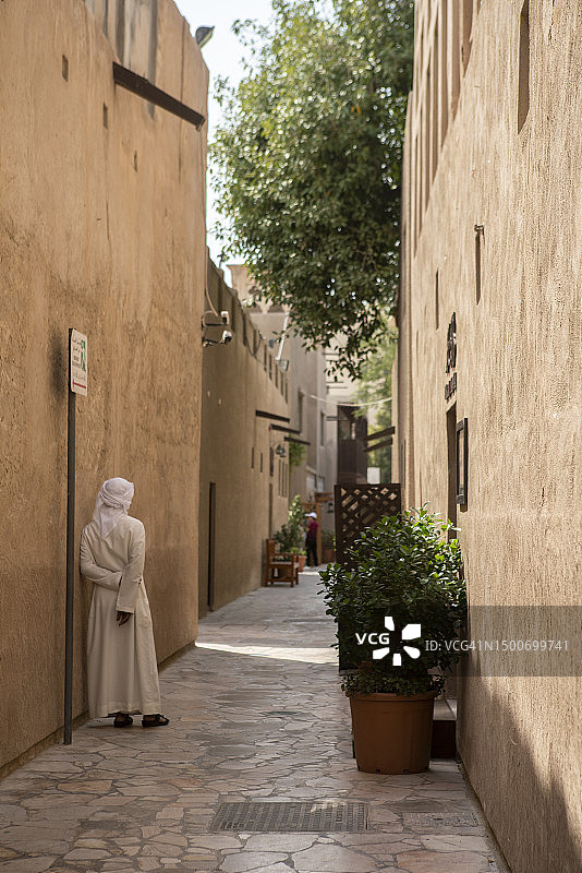 男子在迪拜老城安静的街道上休息图片素材