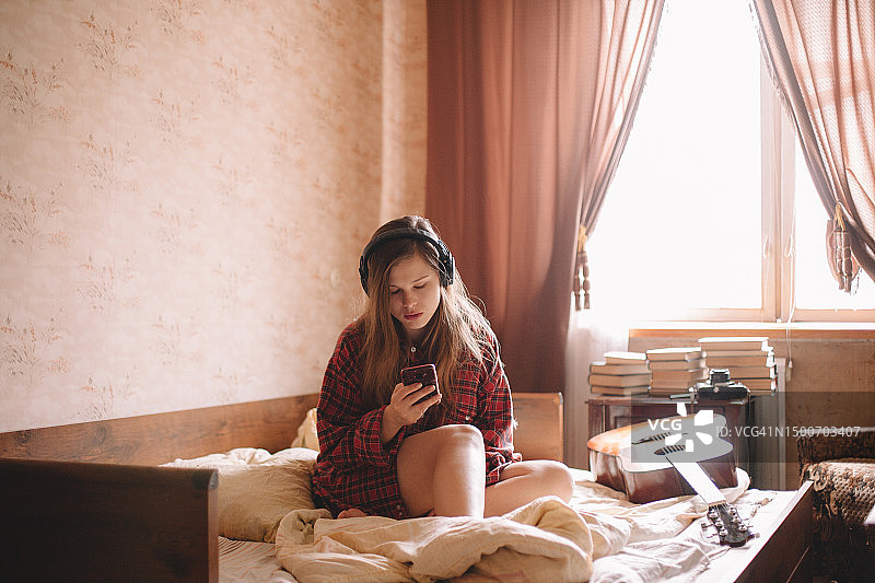 少女戴着耳机使用智能手机听音乐图片素材