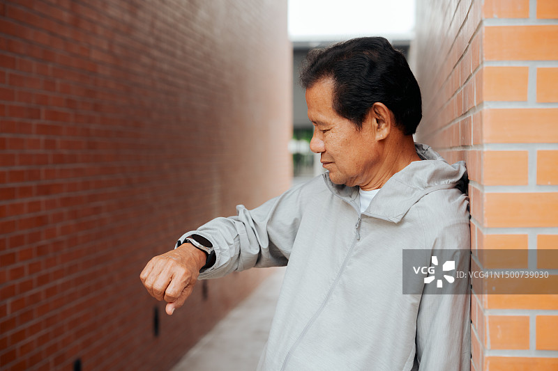 跑步后在公园用智能手表检测心跳的年长男人图片素材