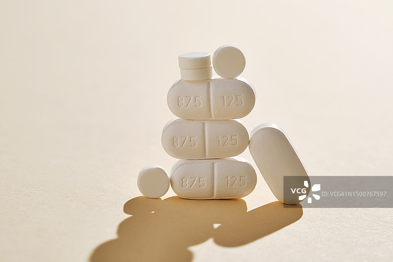 米色背景上的药丸、维生素和营养补充剂以奇异的形状折叠图片素材