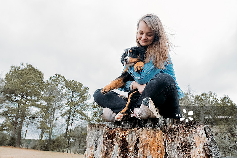 快乐的女人和小狗在户外玩耍，主人和山地犬在田野上玩耍图片素材