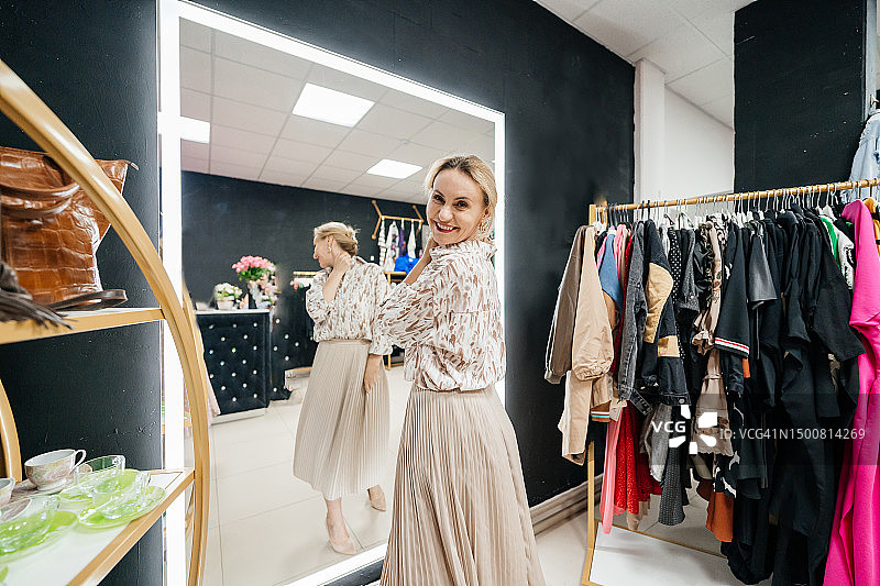 女人在商店的镜子前试穿连衣裙图片素材