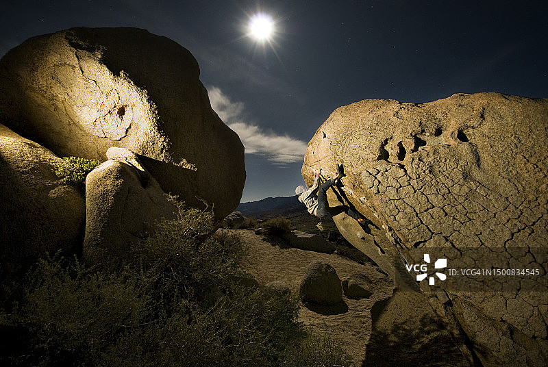 在加利福尼亚州毕夏普，攀岩者在满月下攀登巨石图片素材