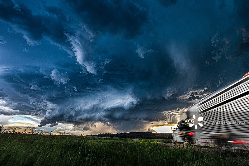 行驶中的卡车驶向巨大的风暴和多云的天空图片素材