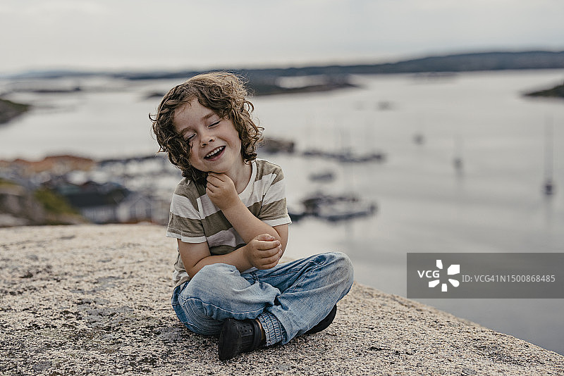 坐在海边的微笑男孩图片素材